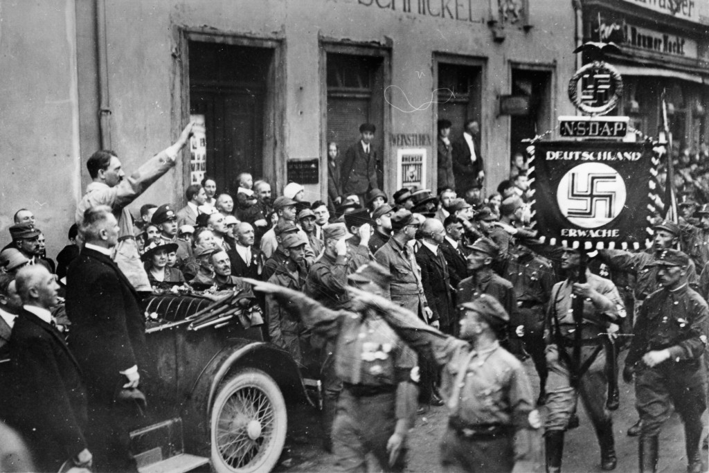 Der Wirtschaftsfachmann Gottfried Feder, der damalige Gauleiter von Thüringen Artur Dinter und Adolf Hitler (v. l. n. r.) nehmen den Vorbeimarsch von SA-Angehörigen ab, 4. Juli 1926