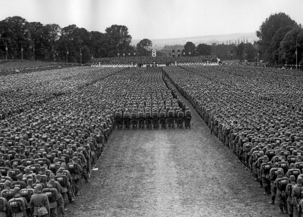 »Appell der Ehrenformationen« im Park von Schloss Tiefurt bei Weimar anlässlich der Feierlichkeiten zur »zehnten Wiederkehr des ersten Reichsparteitages« der NSDAP nach der Neugründung. Blick auf die Tribüne während der Rede Hitlers am 5. Juli 1936, im Hintergrund die Ortslage Alt-Schöndorf