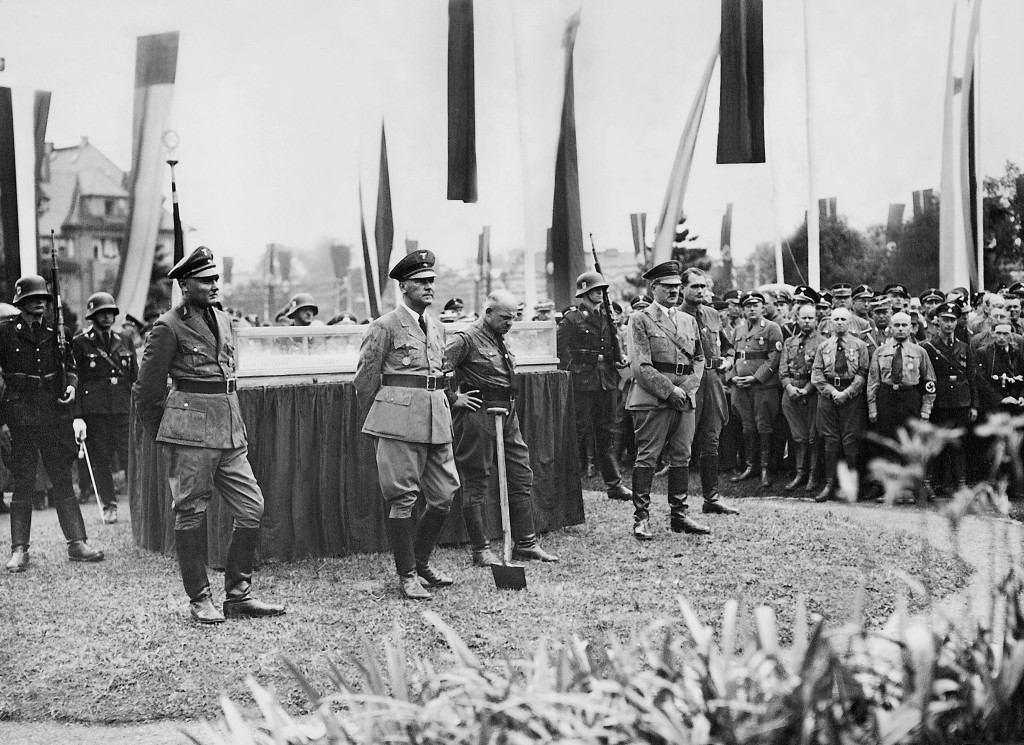 Erster Spatenstich für die Parteibauten am Platz Adolf Hitlers, 4. Juli 1936, Ansprache von Adolf Hitler, v. l. n. r. Max Amann, Wilhelm Frick, Fritz Sauckel, Rudolf Heß. Der Schaukasten mit dem Modell des geplanten Gauforums steht am alten Platz des Vimaria-Brunnens (Carl-Alexander-Sophien-Brunnen)