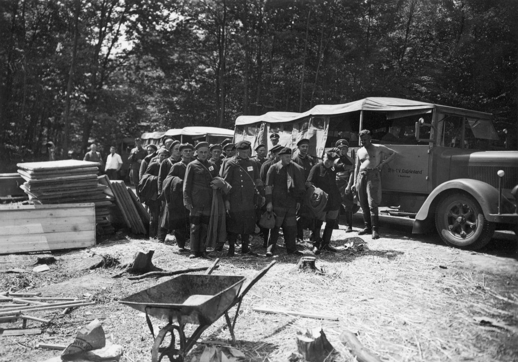 Die ersten »Schutzhaftgefangenen« aus dem KZ Sachsenhausen werden ins Konzentrationslager Buchenwald eingeliefert. Der Lkw im Hintergrund trägt die Aufschrift »IV./​SS-Totenkopf- verband Ostfriesland«, 15. Juli 1937